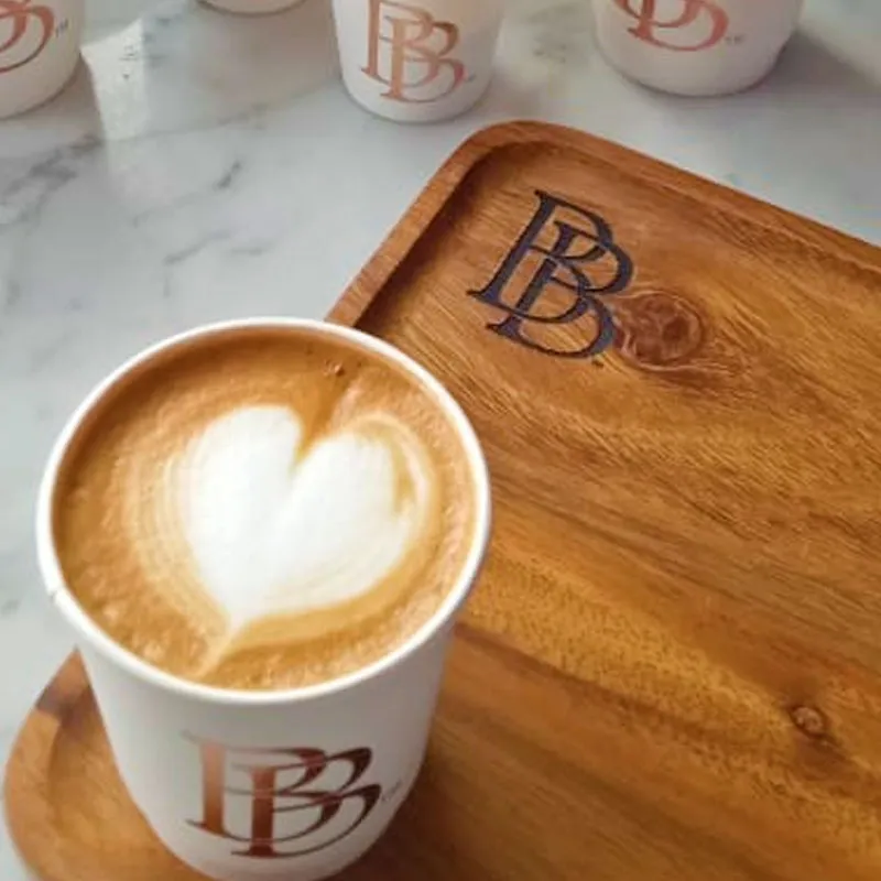 Bebax latte with heart-shaped coffee art on a wooden tray